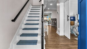 Eine Treppe mit blauen Teppichläufern, einem schwarzen Geländer und weißen Wänden.
