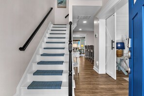Eine Treppe mit blauen Teppichläufern, einem schwarzen Geländer und weißen Wänden.