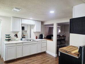 Une cuisine moderne avec des meubles blancs, un plan de travail en bois et un lave-vaisselle encastré.