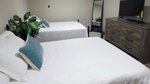 Une chambre avec deux lits, une commode, un miroir et un téléviseur.