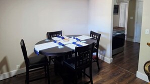 Un coin repas avec une table ronde, quatre chaises et une cuisine en arrière-plan.