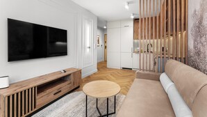 Ein modernes Wohnzimmer mit Flachbildfernseher, Holzmöbeln, einem runden Couchtisch und einer Couch.