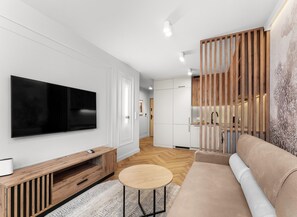 A modern living room with a flat-screen TV, wooden furniture, a round coffee table, and a sofa. - City Łobzów Harmony Apartment (Kraków)