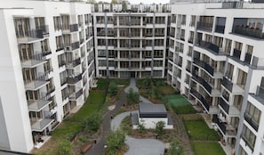 A multi-story residential building with balconies, a central courtyard with pathways, and a small garden area. - City Łobzów Harmony Apartment (Kraków)