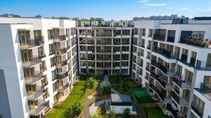 Un edificio residencial de varios pisos con balcones, un patio central y un jardín en la azotea.