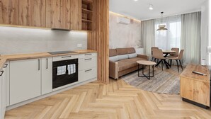 Eine moderne Küche mit Holzausstattung, einem eingebauten Backofen und einem Essbereich mit Sofa und Stühlen.