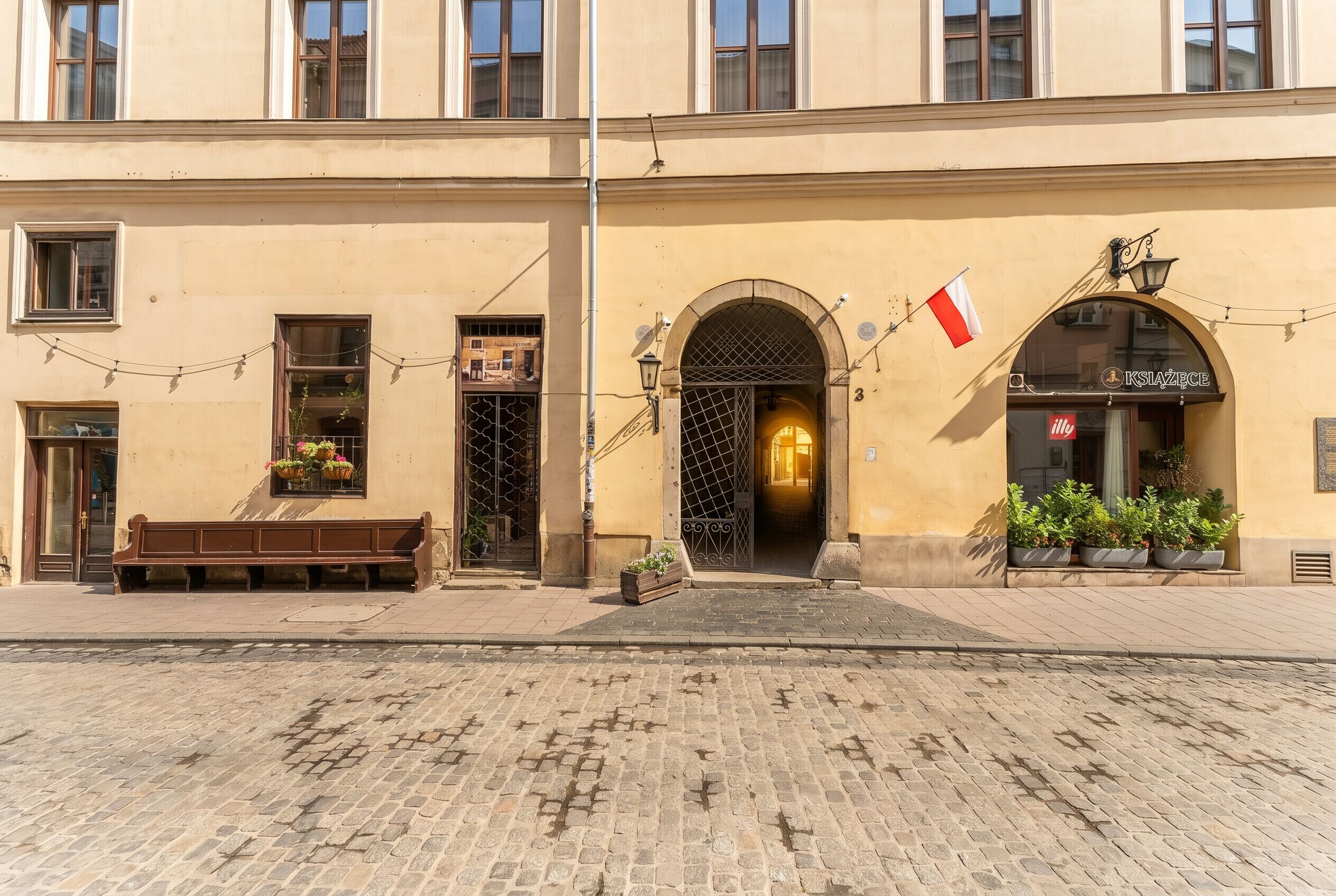A building with a large arched entrance, a bench outside, and a flag.