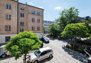 Ein mehrstöckiges Gebäude mit einem gepflasterten Innenhof, parkenden Autos und Bäumen.