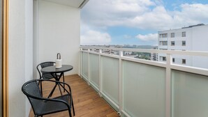 Ein Balkon mit Tisch und Stühlen, Blick auf Gebäude und einem klaren Himmel.