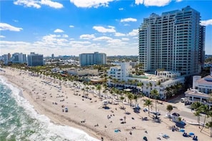 Eine Küstenstadt mit Strand, Hochhotels und blauem Himmel.
