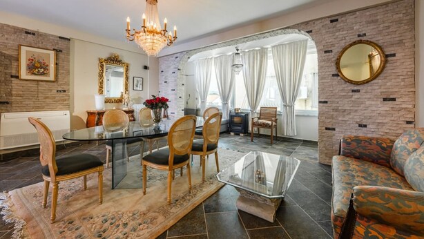 Un coin repas avec une table et des chaises en verre, un lustre et un canapé.