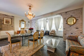 A dining area with a glass table and chairs, a chandelier, and a sofa. - Charming 1BR Apartment in Shkod r City Center (Shkodër)