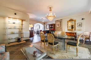 A dining area with a glass table, wicker chairs, a chandelier, and a mirror. - Charming 1BR Apartment in Shkod r City Center (Shkodër)