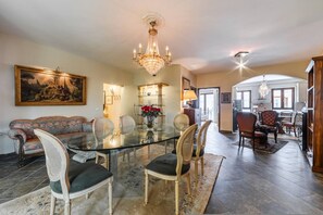 A dining area with a glass table, chairs, a chandelier, a sofa, and a painting on the wall. - Charming 1BR Apartment in Shkod r City Center (Shkodër)