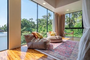 A modern room with large windows, a patterned rug, and a view of lush greenery. - A Cliff Residence Villa (Ubud)