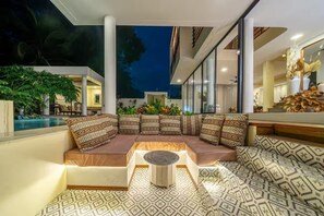 A modern living area with a sofa set, a round coffee table, and a patterned floor. - A Cliff Residence Villa (Ubud)