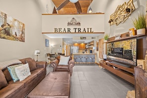 Ein Wohnzimmer mit einem braunen Ledersofa, einem Fernseher und einem Schild mit der Aufschrift 'BEAR TRAIL'.
