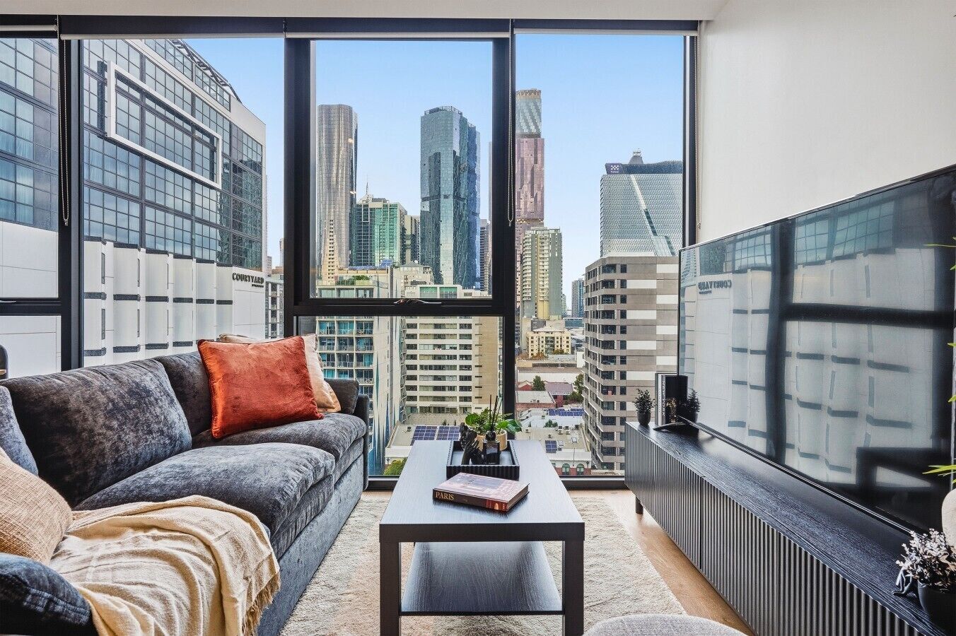 Una sala de estar moderna con vista a la ciudad, un sofá, una mesa de centro y una estantería.