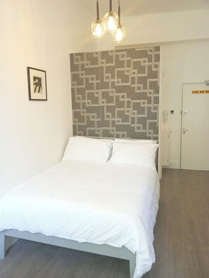 Une chambre à coucher avec un lit, une tête de lit à motifs, une porte et un tableau encadré au mur.