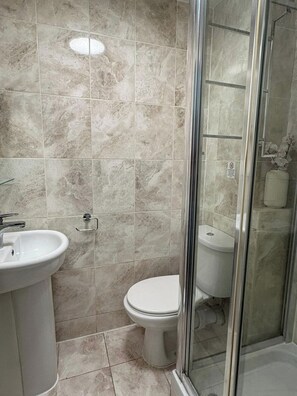 Ein Badezimmer mit Waschbecken, Toilette und Duschkabine aus Glas.