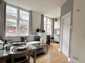 Ein modernes Apartment mit Essbereich, einer Couch und einer Küche.