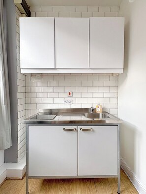 Eine moderne Küche mit weißen Schränken, einer Edelstahl-Arbeitsplatte und einem eingebauten Backofen.