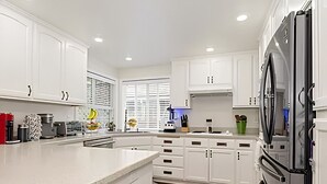 Una cocina moderna con armarios blancos, un refrigerador grande y una isla curva.