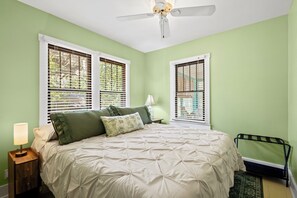Un dormitorio con cama, mesita de noche, lámpara y ventilador de techo.