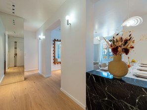 Ein modernes Interieur mit einer Marmorarbeitsplatte, einer Vase mit Trockenblumen und einem Essbereich mit Blick.