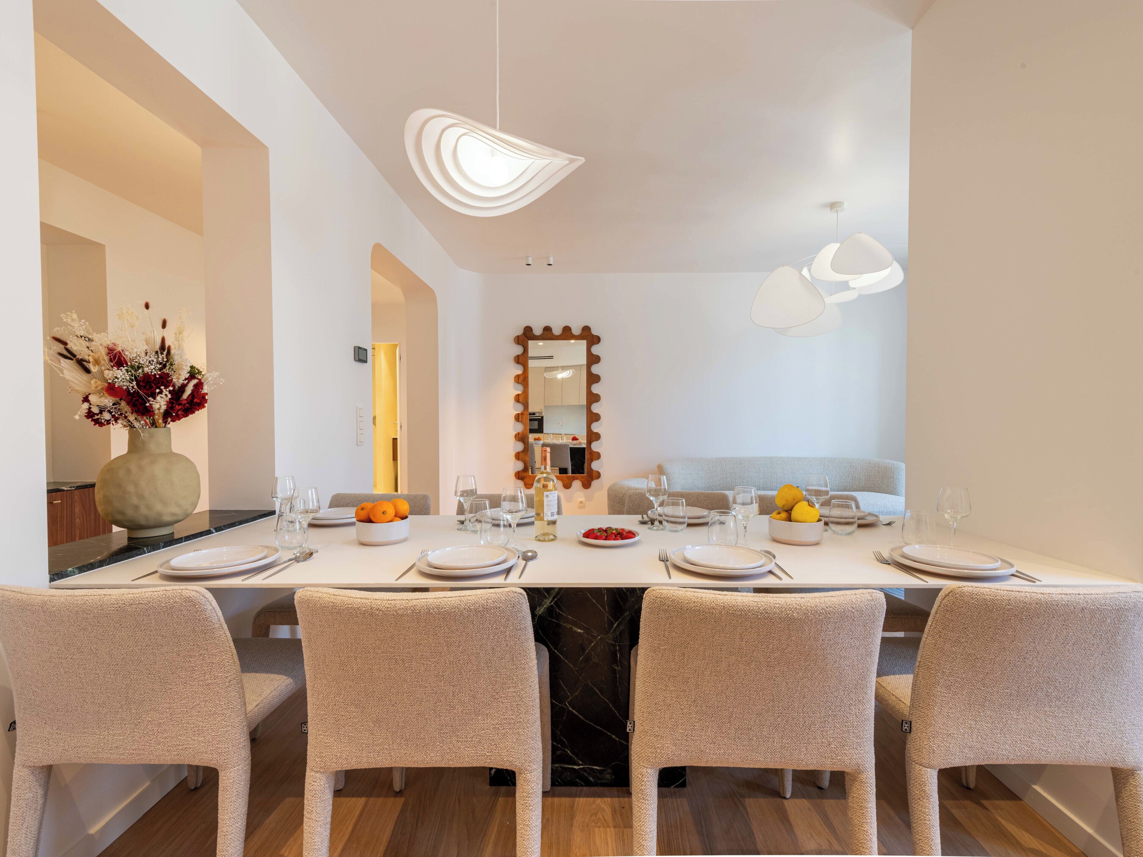 Une salle à manger moderne avec une longue table, des chaises et un miroir.