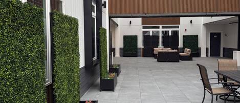 Un espacio exterior moderno con terraza, asientos y jardineras.