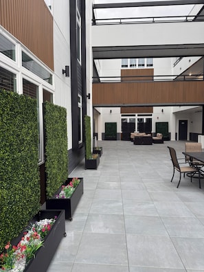 Un espacio exterior moderno con terraza, asientos y jardineras.