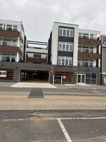Un edificio de varios pisos con entrada para coches, un letrero que dice Coral Sands Condominium y un camino de acceso con portón.
