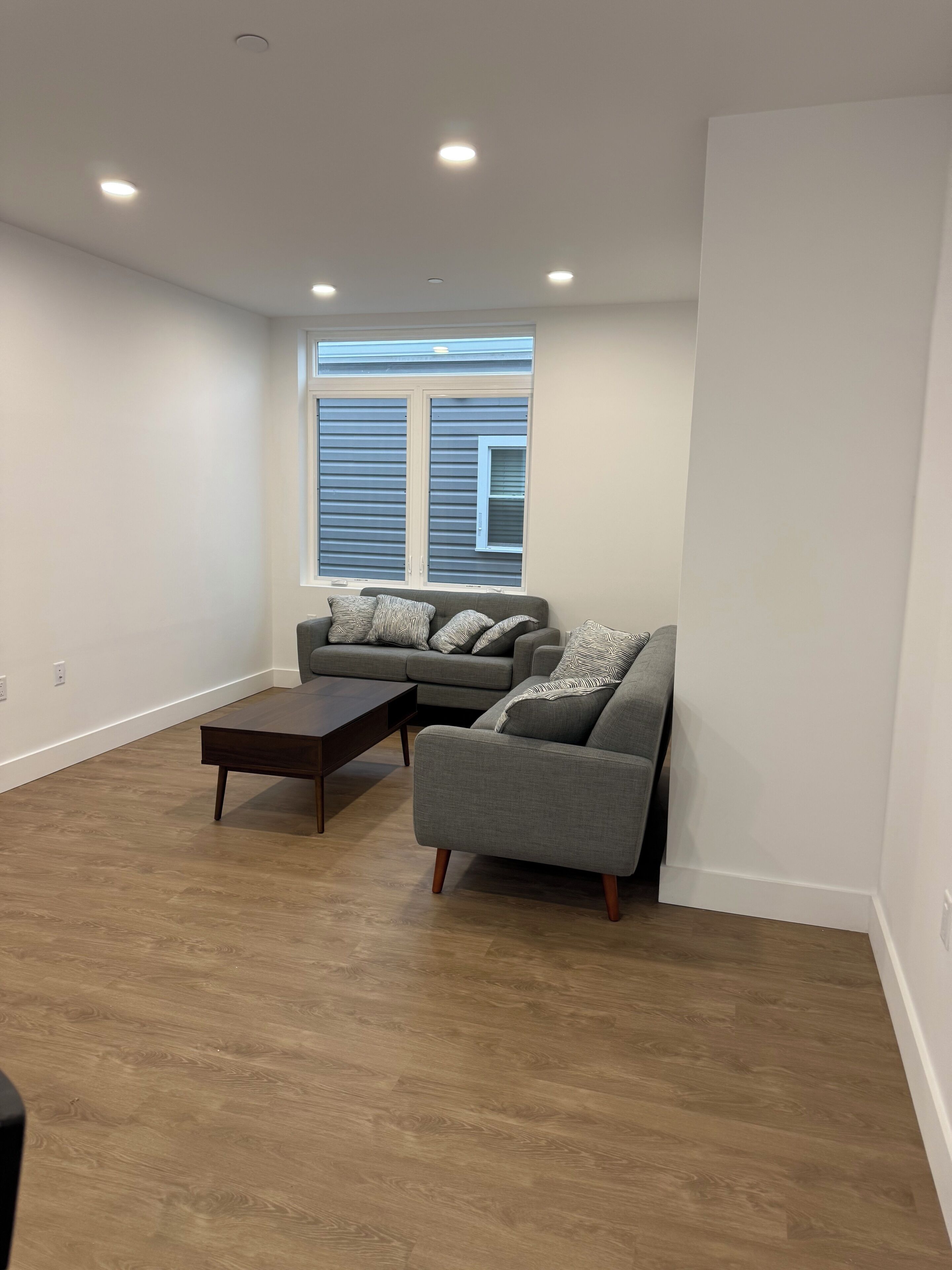 A living room with a sofa, a coffee table, and a window with blinds.