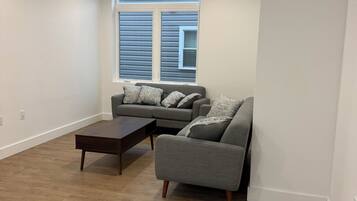 A living room with a sofa, a coffee table, and a window with blinds.