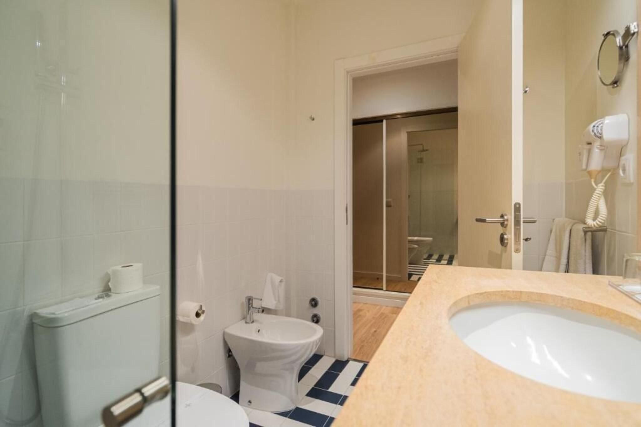 Een badkamer met toilet, hygiëneschuimer en wastafel.