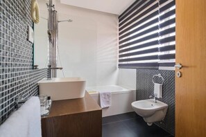 A modern bathroom with a freestanding bathtub, a sink with a mirror, and a bidet.