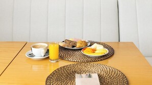 A dining area with a table set for breakfast, a painting of a lighthouse, and a woven placemat. - Residencial Farol (Ilhavo)