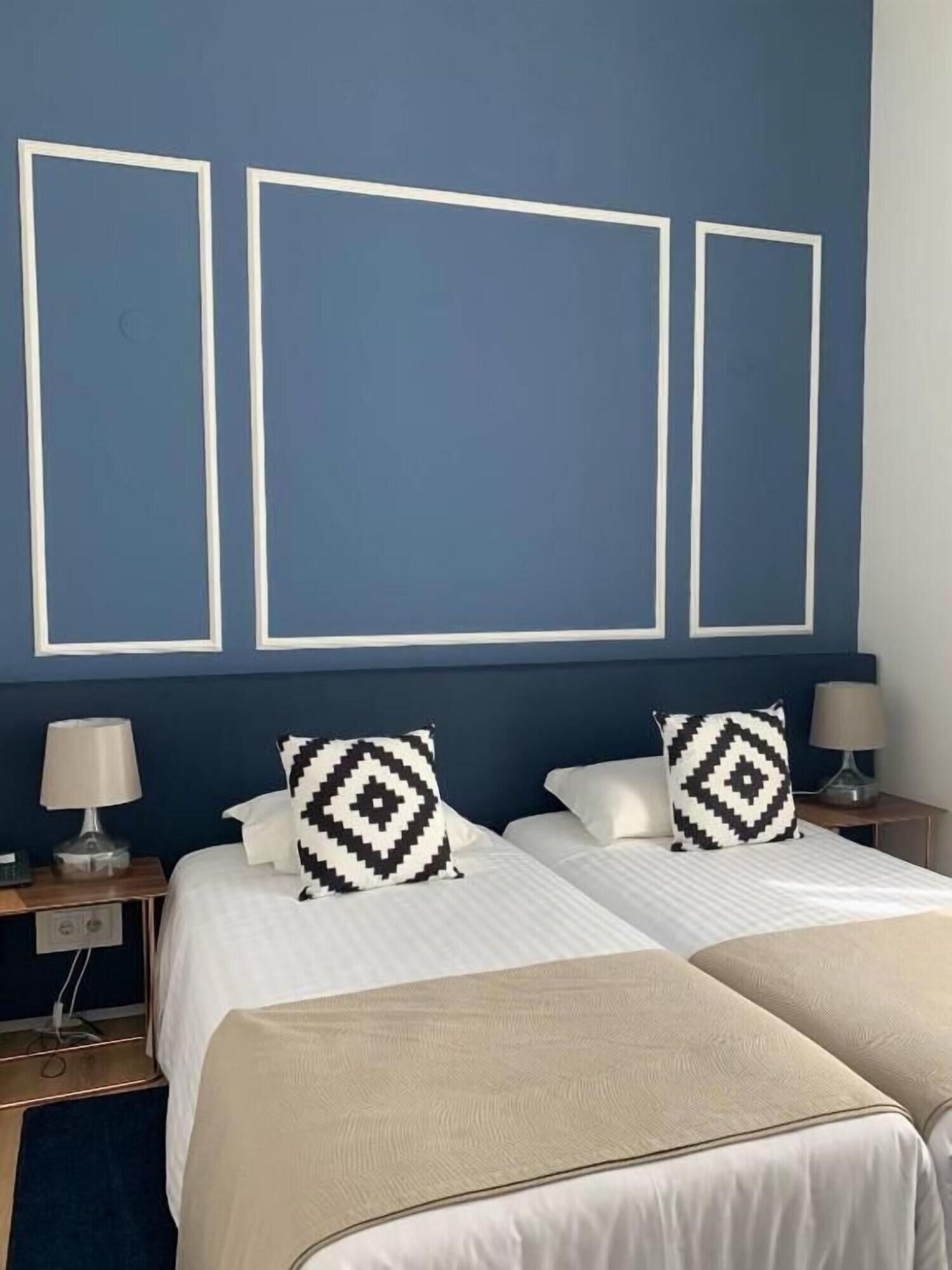 Ein Hotelzimmer mit einem Bett, zwei Nachttischen und einer Wand mit drei rechteckigen Rahmen.