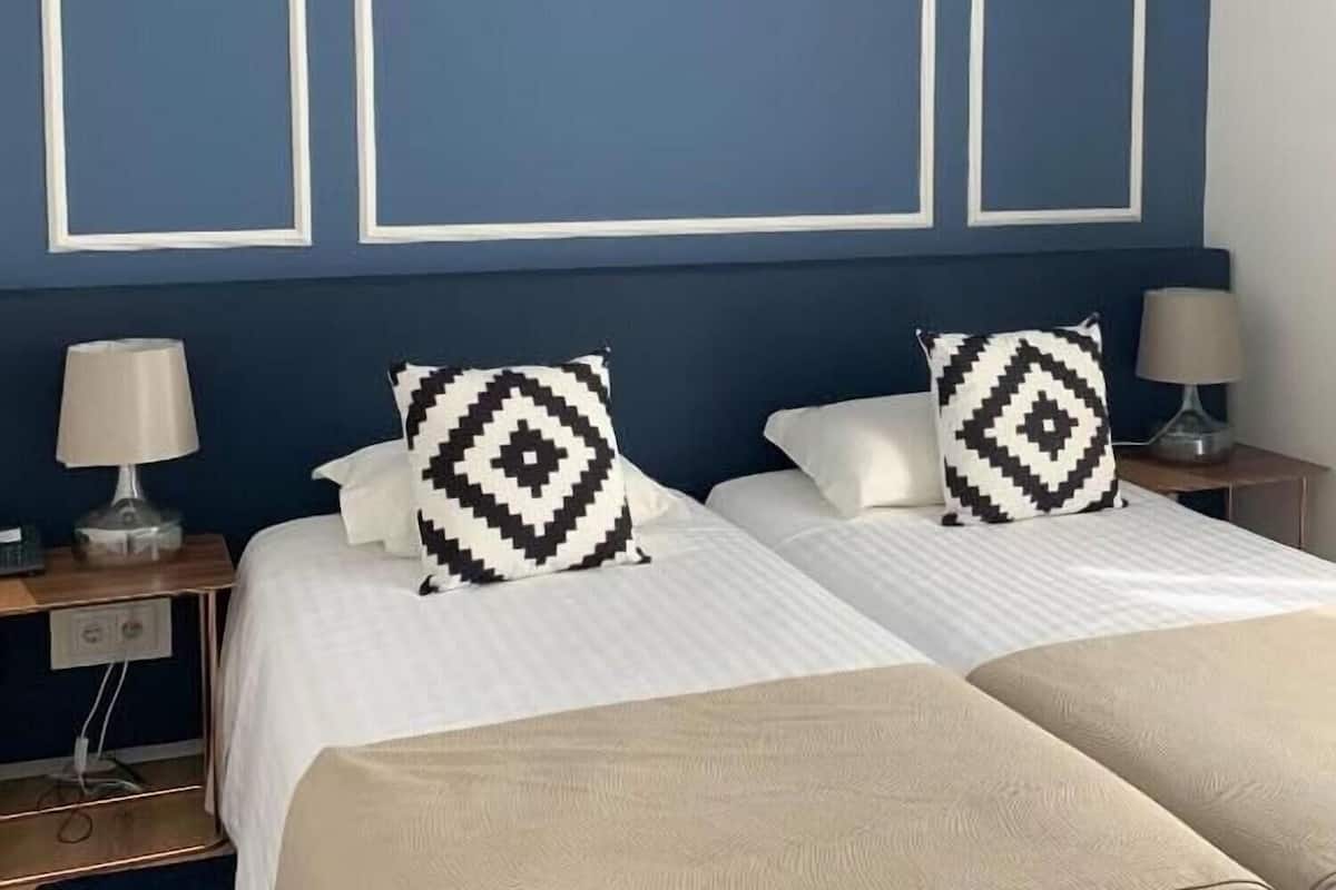 Ein Hotelzimmer mit einem Bett, zwei Nachttischen und einer Wand mit drei rechteckigen Rahmen.