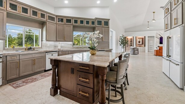 A spacious kitchen with a large island, dark wooden cabinets, and a view to the outdoors.