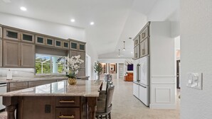 A modern kitchen with a large island, built-in cabinets, and a view to the outdoors.