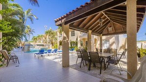 A covered outdoor area with a pool, lounge chairs, and a table with chairs. - Tropical Getaway w/ Pool & Patio @ Wacamaya Condos (Noord)