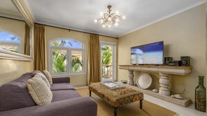 A living room with a sofa, a coffee table, a television, and a fireplace. - Tropical Getaway w/ Pool & Patio @ Wacamaya Condos (Noord)