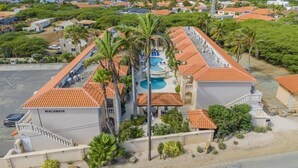 A resort with a swimming pool, palm trees, and a 'WACAMAYA' sign. - Tropical Getaway w/ Pool & Patio @ Wacamaya Condos (Noord)