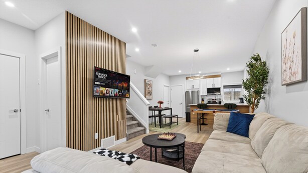 Una sala de estar moderna con un sofá, una mesa de centro y un televisor montado en la pared.