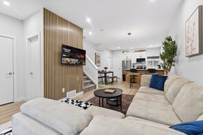 A modern living room with a sofa, a coffee table, and a TV mounted on a wall. - The Executive Escape|Spacious 3BR Near Downtown|Free parking|Free WiFi|Pooltable (Edmonton)