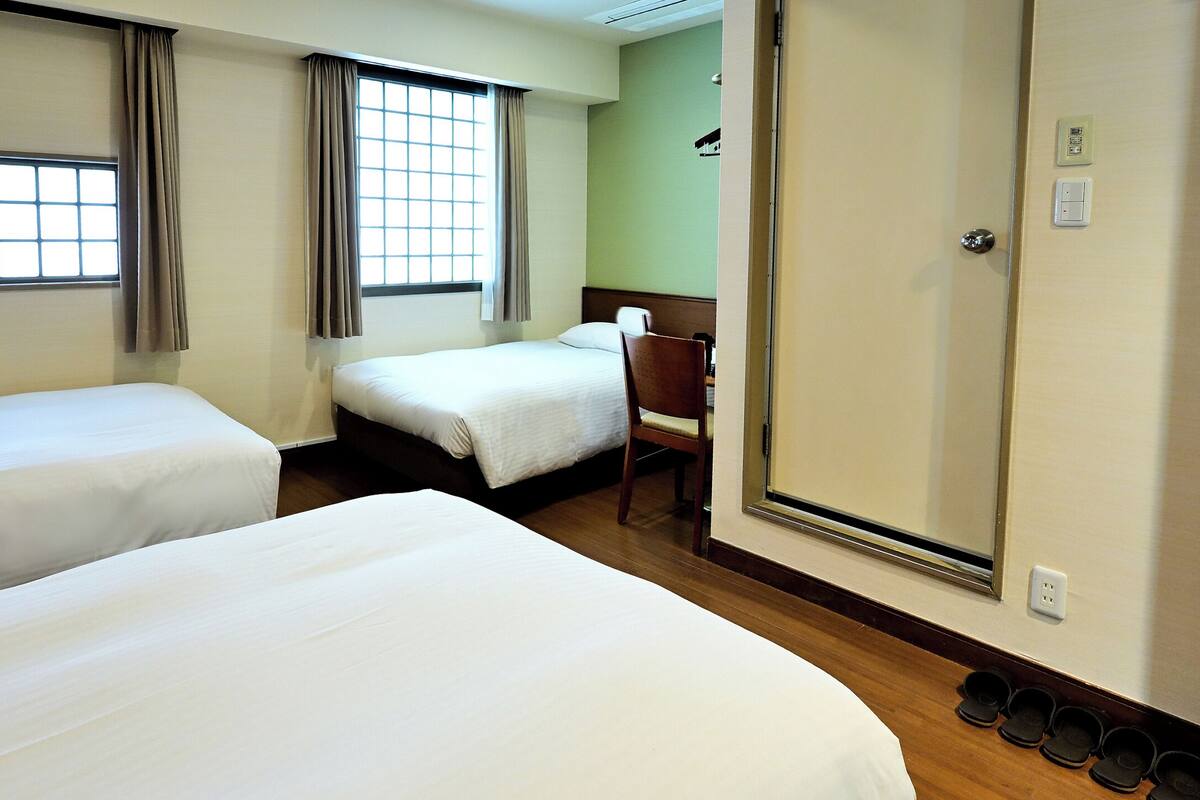 Habitación de hotel con dos camas, piso de madera, una silla y un espejo.