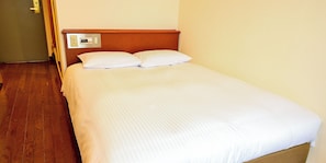 Ein Hotelzimmer mit Holzboden, einem Bett mit weißer Bettwäsche und einer Wandbedienung.