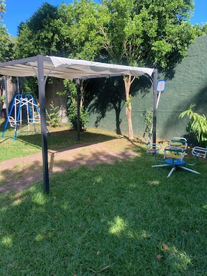 A covered patio area with a swing set and a small table.